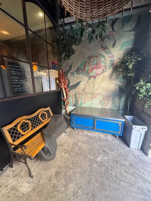 a wooden bench sitting in front of a wall with a painting on it