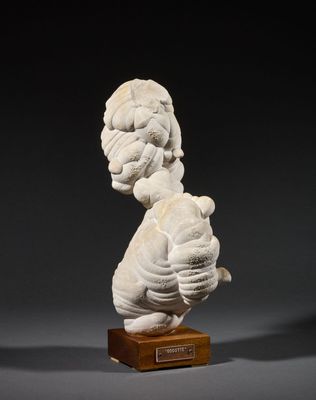 a white sculpture of a woman holding a child on a wooden base