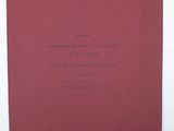 a red book with black writing on it sitting on a white surface