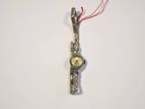 a silver watch with a red string hanging from it ' s side