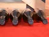 four bottles of wine are lined up on a red cloth