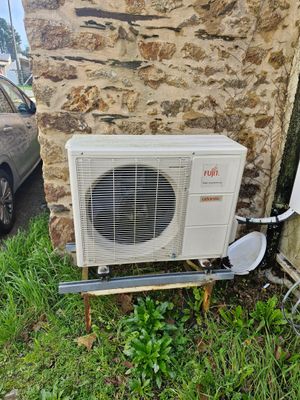 un climatiseur installé à l'extérieur d'une maison, à côté d'une voiture