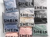 une pile de chemises de différentes couleurs posée sur une surface blanche