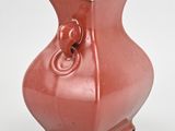 a red vase that has a handle on it