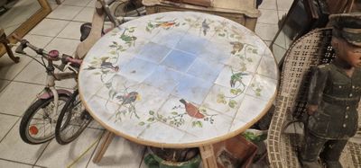 une table ornée d'un motif d'oiseau, avec une poupée assise dans un fauteuil en osier à côté