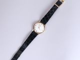 a black and gold watch with a white face on a white surface
