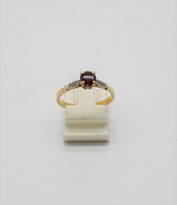 a close up of a gold ring with a red stone on it