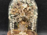 un dôme en verre renfermant un vase de fleurs