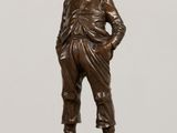 bronze statue of a boy standing on a pedestal with his hands on his hips