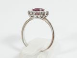 a close up of a diamond and ruby ring on a white surface