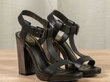 the heel of a pair of black high heel sandals on a wooden table