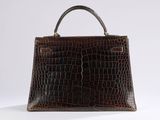a brown crocodile skin handbag on a white surface