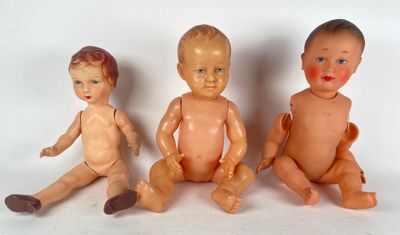 three dolls sitting next to each other on a white surface