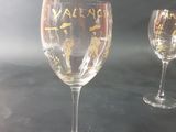 two wine glasses with gold writing on them on a table
