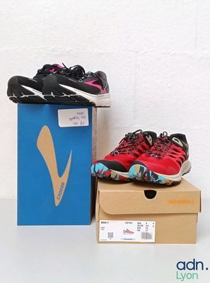 une paire de chaussures de course rouges et noires posée sur une boîte en carton