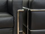 pair of black leather lounge chairs with chrome legs