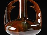 a brown vase sitting on a table with a black background