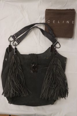 black purse with tassels hanging from it on a bed