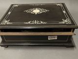 an old black and white box with a gold decoration on it