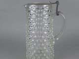 a clear glass pitcher with a handle on a gray background