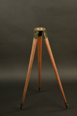 a wooden tripod with a brass plate on top of it