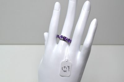 une main sur laquelle est passée une bague sertie de pierres d'améthoralite