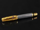 a silver and gold pen sitting on top of a black surface