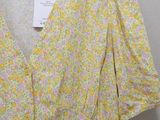 a close up of a yellow and pink floral dress on a hanger