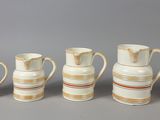 several white and brown vases are lined up against a gray background