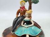 une figurine représentant un homme et une femme assis sur un rocher