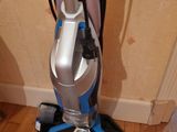 a vacuum that is sitting on the floor next to a remote control