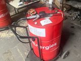 un fût rouge posé sur une charrette dans un garage