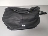 black leather bag with a tag on it sitting on a table