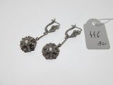 une paire de boucles d'oreilles en argent ornées de fleurs, avec une étiquette de prix
