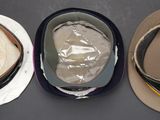 three hats are lined up on a table with plastic wrap around them