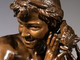 bronze statue of a boy holding a bird in his hand