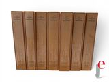six books are lined up in a row on a white surface