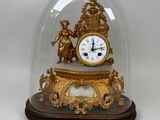 a gold clock under a glass dome on a table