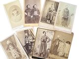 Plusieurs vieilles photos de personnes sont exposées sur une surface blanche