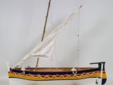 wooden model of a sailboat with a white sail on a wooden stand