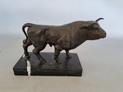 statue d'un taureau posée sur un socle en marbre, sur fond blanc
