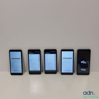 Quatre téléphones portables sont alignés sur une table devant un fond blanc