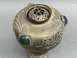 a gold vase with a green and blue decoration on it