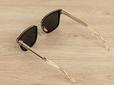 black and gold cat eye sunglasses on a wooden surface