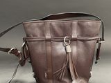 leather handbag with tassels on a grey background