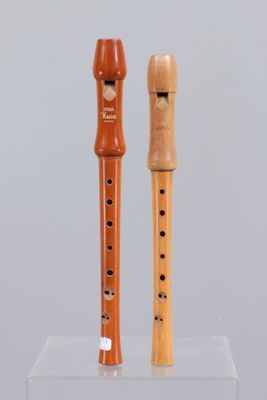 two wooden flutes on display on a clear stand