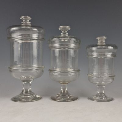 Trois bocaux en verre transparent munis de couvercles sont posés sur une table