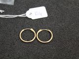 two pairs of gold hoop earrings on a black surface with a price tag