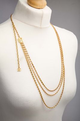 a mannequin wearing a gold chain necklace with a cross on it
