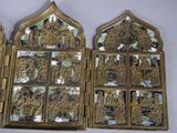 three gold and silver metal religious items on display on a white surface